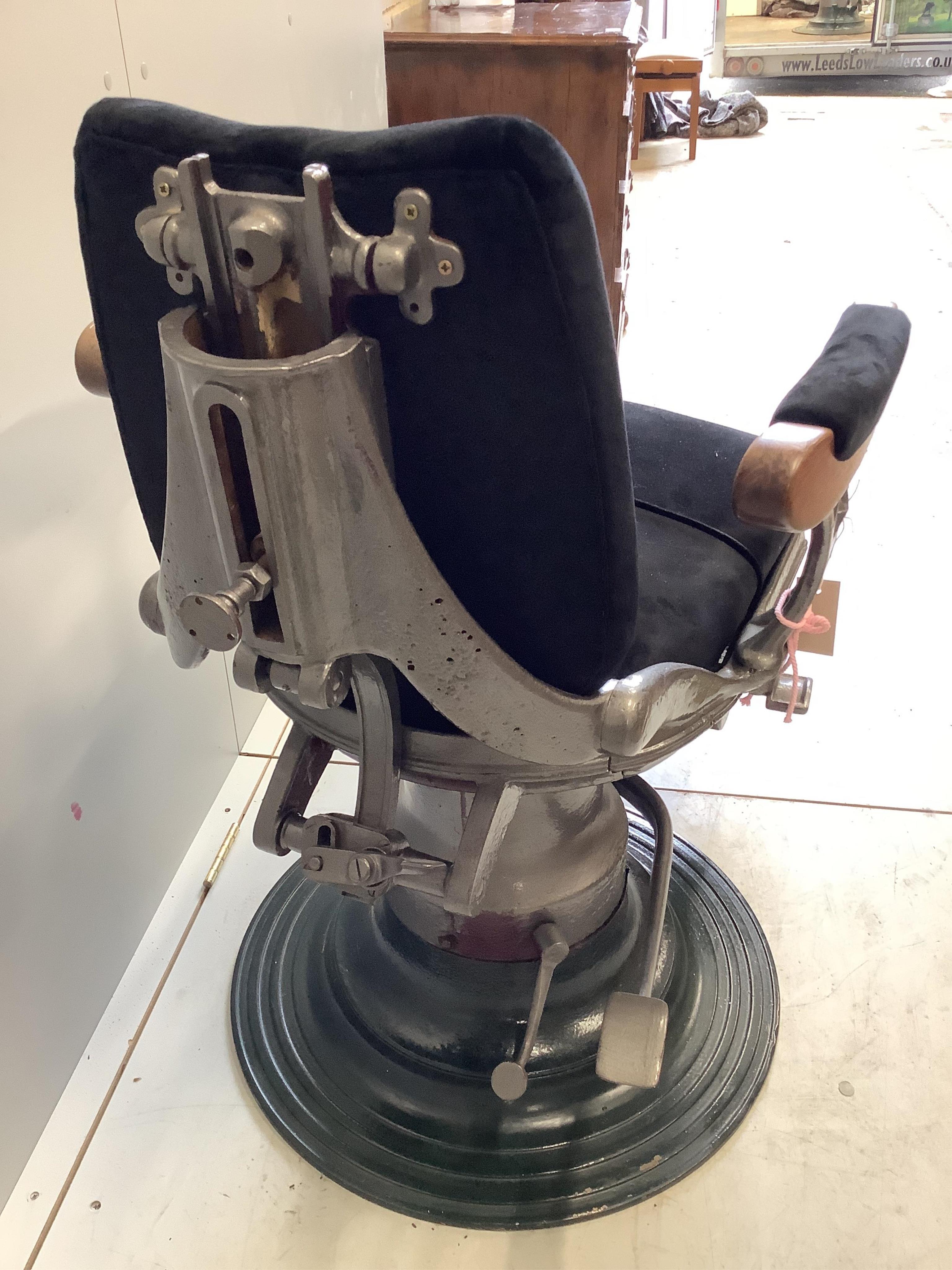 A pair of heavy cast iron upholstered and teak barber's chairs. Condition - fair to good, one with loose arms